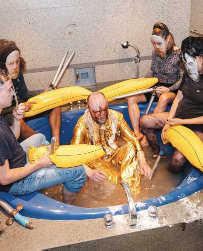 Heaven: masked participants surround John Robinson, coated in sauces and flour, in an inflatable pool at DeNode Foundation, Ghent.
