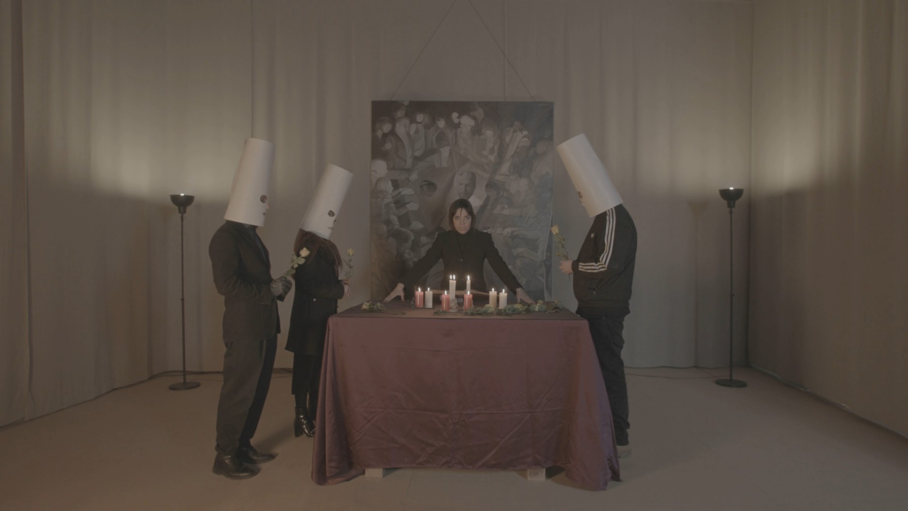 Still — masked participants holding roses gather around the table as the medium presides over the candles.